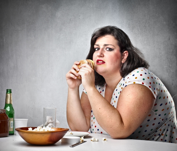 Fat woman feeling guilty while eating junk food